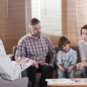 Rear,View,Of,Female,Psychologist,Helping,Young,Family,With,A