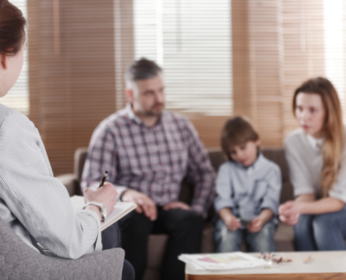 Rear,View,Of,Female,Psychologist,Helping,Young,Family,With,A