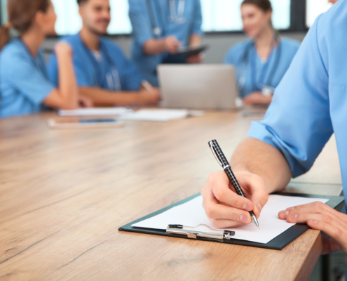 Medical,Student,With,Clipboard,And,His,Groupmates,Studying,In,University