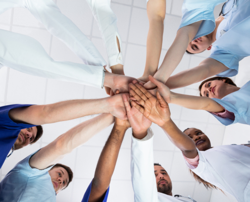 Low,Angle,View,Of,Doctor,Stacking,Hands,Together,In,Hospital