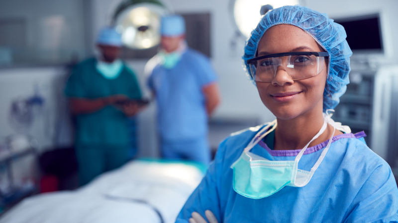 Portrait,Of,Female,Surgeon,Wearing,Scrubs,And,Protective,Glasses,In