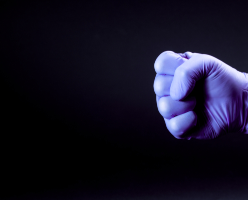 Fist,Of,Right,Man,Hand,In,A,Purple,Medical,Glove