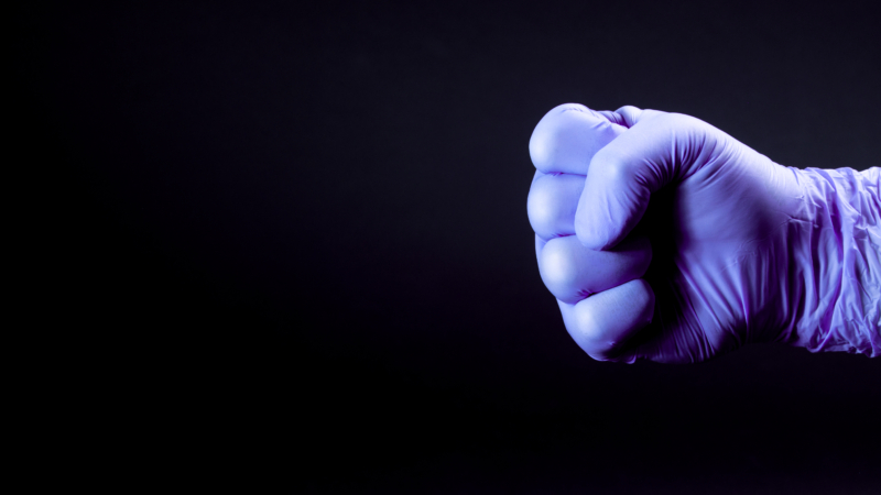 Fist,Of,Right,Man,Hand,In,A,Purple,Medical,Glove