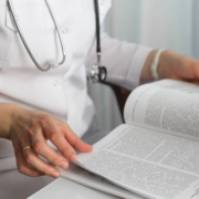 Hands,Of,A,Female,Doctor,Holding,A,Medical,Journal,In