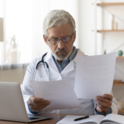 Serious,Professional,Senior,Elderly,Doctor,Doing,Paperwork,Checking,Medical,Documents