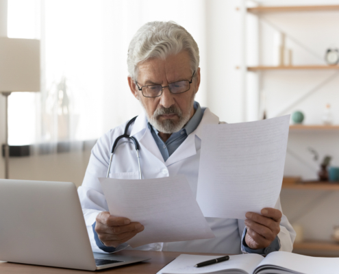 Serious,Professional,Senior,Elderly,Doctor,Doing,Paperwork,Checking,Medical,Documents