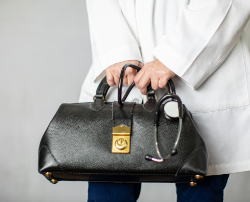 Female,Physician,Holding,A,Black,Leather,Doctor’s,Bag,Heading,To