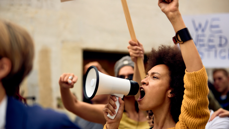 Young,African,American,Woman,With,Raised,Fist,Shouting,Through,Megaphone