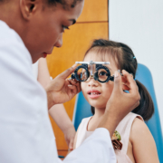 Pediatric,Optometrist,Helping,Little,Girl,To,Put,On,Test,Glasses