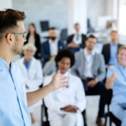 Young,Doctor,Talking,To,Group,Of,His,Colleagues,And,Business