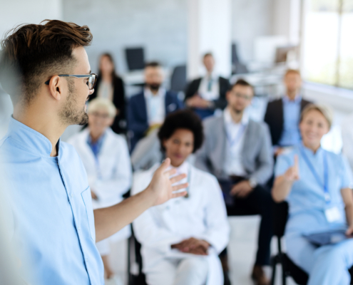 Young,Doctor,Talking,To,Group,Of,His,Colleagues,And,Business
