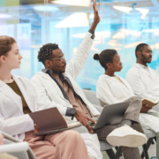 Multi-ethnic,Group,Of,People,Wearing,Lab,Coats,Sitting,In,Row