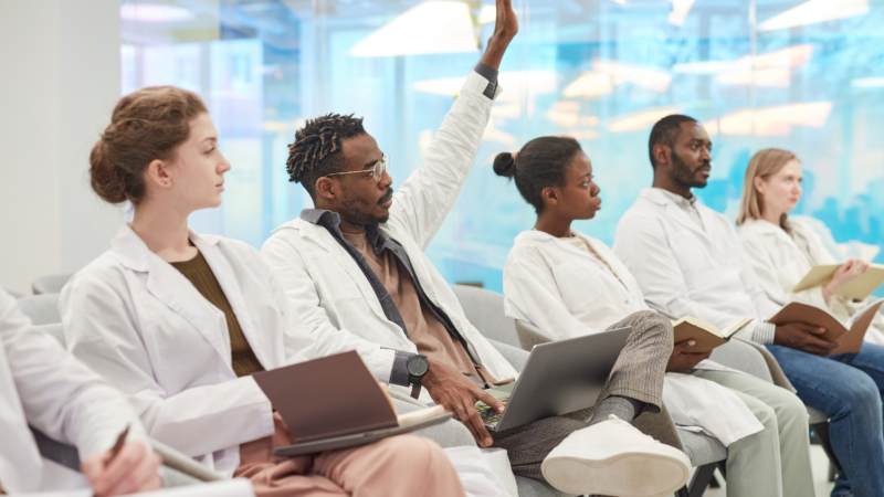 Multi-ethnic,Group,Of,People,Wearing,Lab,Coats,Sitting,In,Row