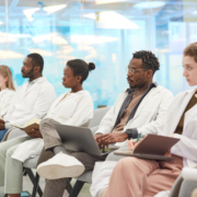 Multi-ethnic,Group,Of,People,Wearing,Lab,Coats,Sitting,In,Row