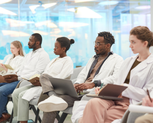 Multi-ethnic,Group,Of,People,Wearing,Lab,Coats,Sitting,In,Row