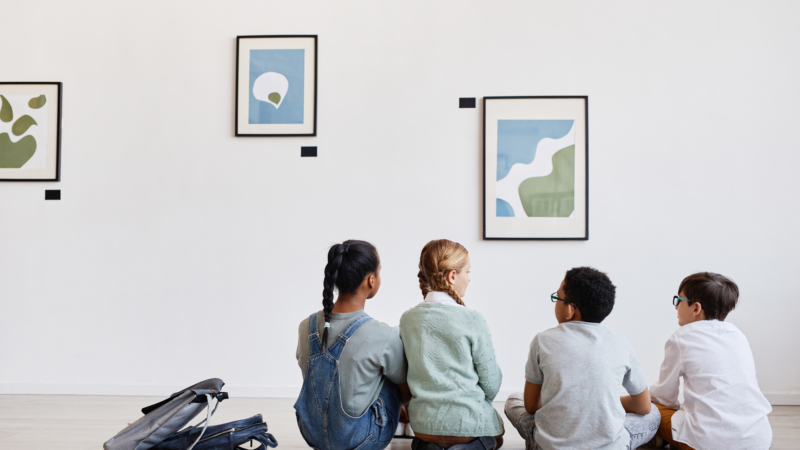 Back,View,At,Diverse,Group,Of,Children,Sitting,On,Floor