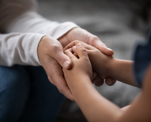 Close,Up,Compassionate,Young,Foster,Parent,Holding,Hands,Of,Little