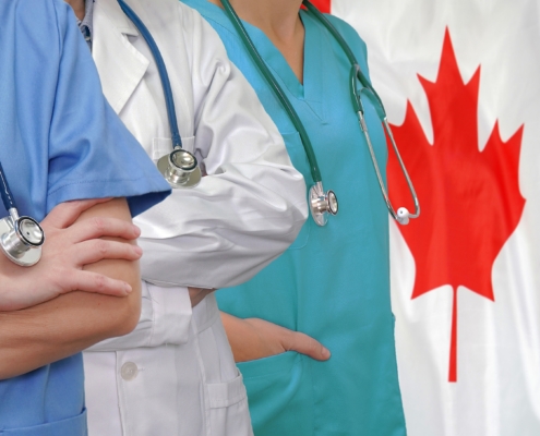 Three,Doctors,With,Stethoscope,In,Standing,On,Canada,Flag,Background.