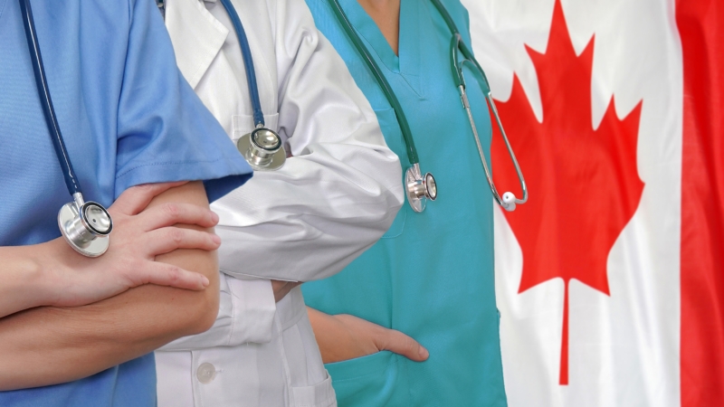 Three,Doctors,With,Stethoscope,In,Standing,On,Canada,Flag,Background.