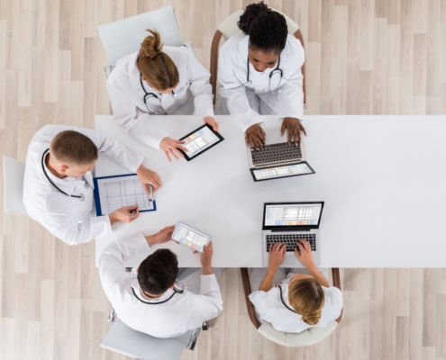 Medical,Doctor,Group,Meeting,At,Desk,With,Laptop,Computer
