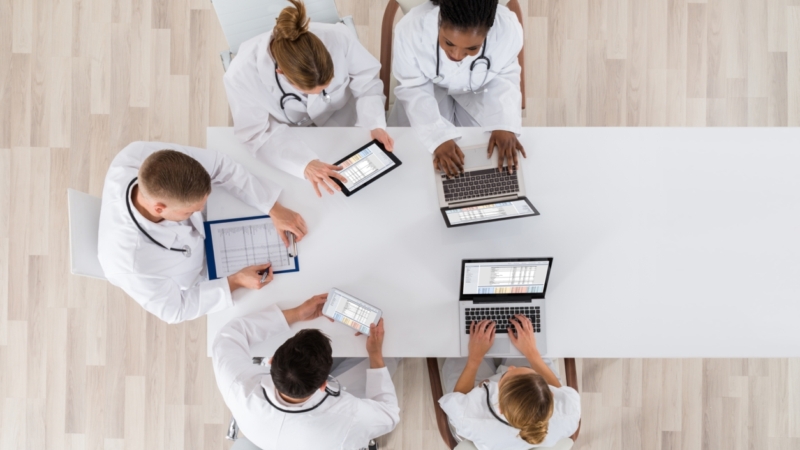 Medical,Doctor,Group,Meeting,At,Desk,With,Laptop,Computer