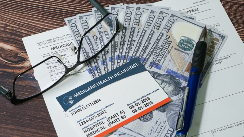 Fake,Medicare,Cardand,Fake,Cash,With,Eyeglasses,And,A,Pen.