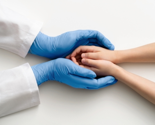 The,Doctor’s,Gloved,Hands,Hold,The,Child’s,Hands.,Medical,Concept.
