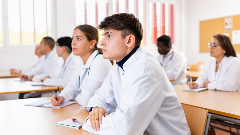 Young,Man,Medical,Student,In,White,Coat,Attedning,Classes,In