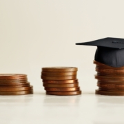 Black,Graduation,Cap,On,Stocks,Of,Coins,,Depicting,Strong,Effort