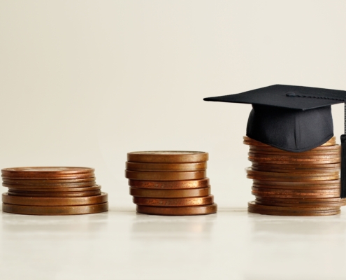 Black,Graduation,Cap,On,Stocks,Of,Coins,,Depicting,Strong,Effort