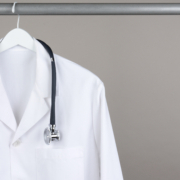 A,Doctor’s,Lab,Coat,And,Stethoscope,On,Hanger,Against,A