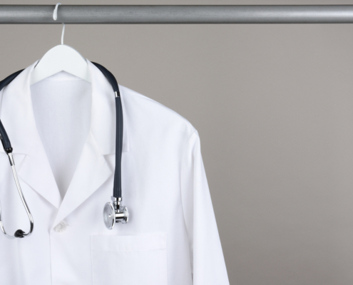 A,Doctor’s,Lab,Coat,And,Stethoscope,On,Hanger,Against,A