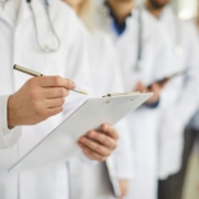 Professional,Doctor,Wearing,Uniform,Taking,Notes,In,Clipboard,Journal,,Physician