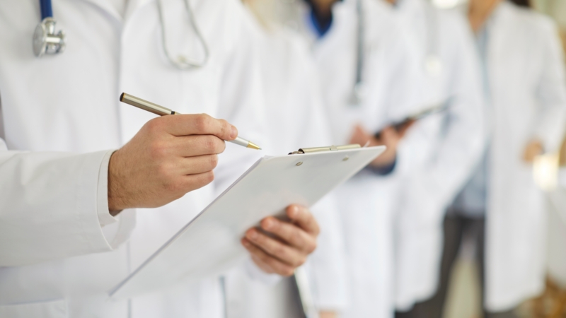 Professional,Doctor,Wearing,Uniform,Taking,Notes,In,Clipboard,Journal,,Physician