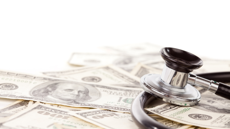Stethoscope,Laying,On,Stacks,Of,Hundred,Dollar,Bills,With,Narrow