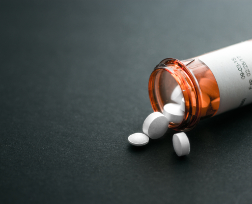 White,Pills,Spilling,Out,Of,A,Toppled,Bright,Red,Orange