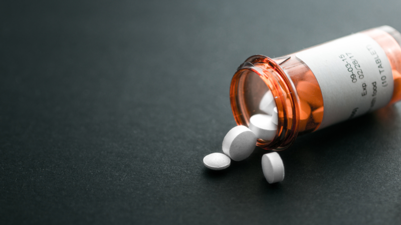 White,Pills,Spilling,Out,Of,A,Toppled,Bright,Red,Orange