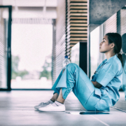 Side,View,Of,Nurse,Sitting,On,Floor,In,Hospital,Corridor