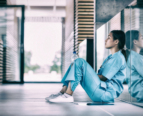 Side,View,Of,Nurse,Sitting,On,Floor,In,Hospital,Corridor