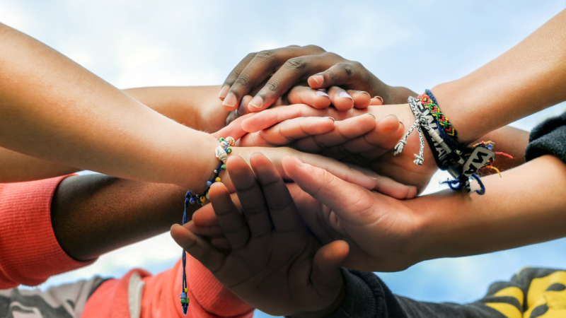 Multiracial,Teenagers,Joining,Hands,Together,In,Cooperation
